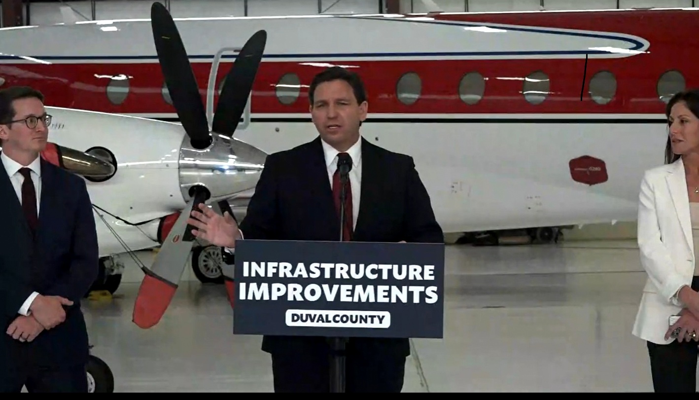 Ron DeSantis in a military uniform standing in front of a plane