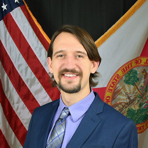 A man wearing a suit and tie smiling at the camera