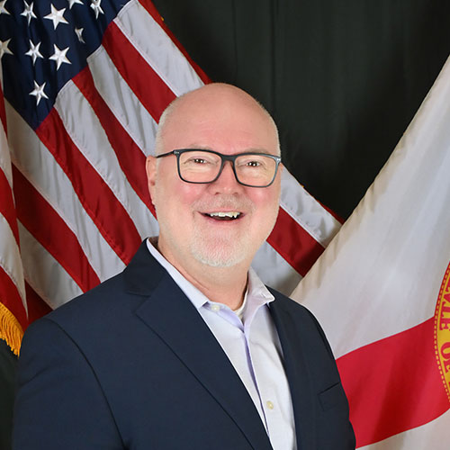 A man wearing a suit and tie smiling at the camera