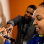 Two people writing on a whiteboard
