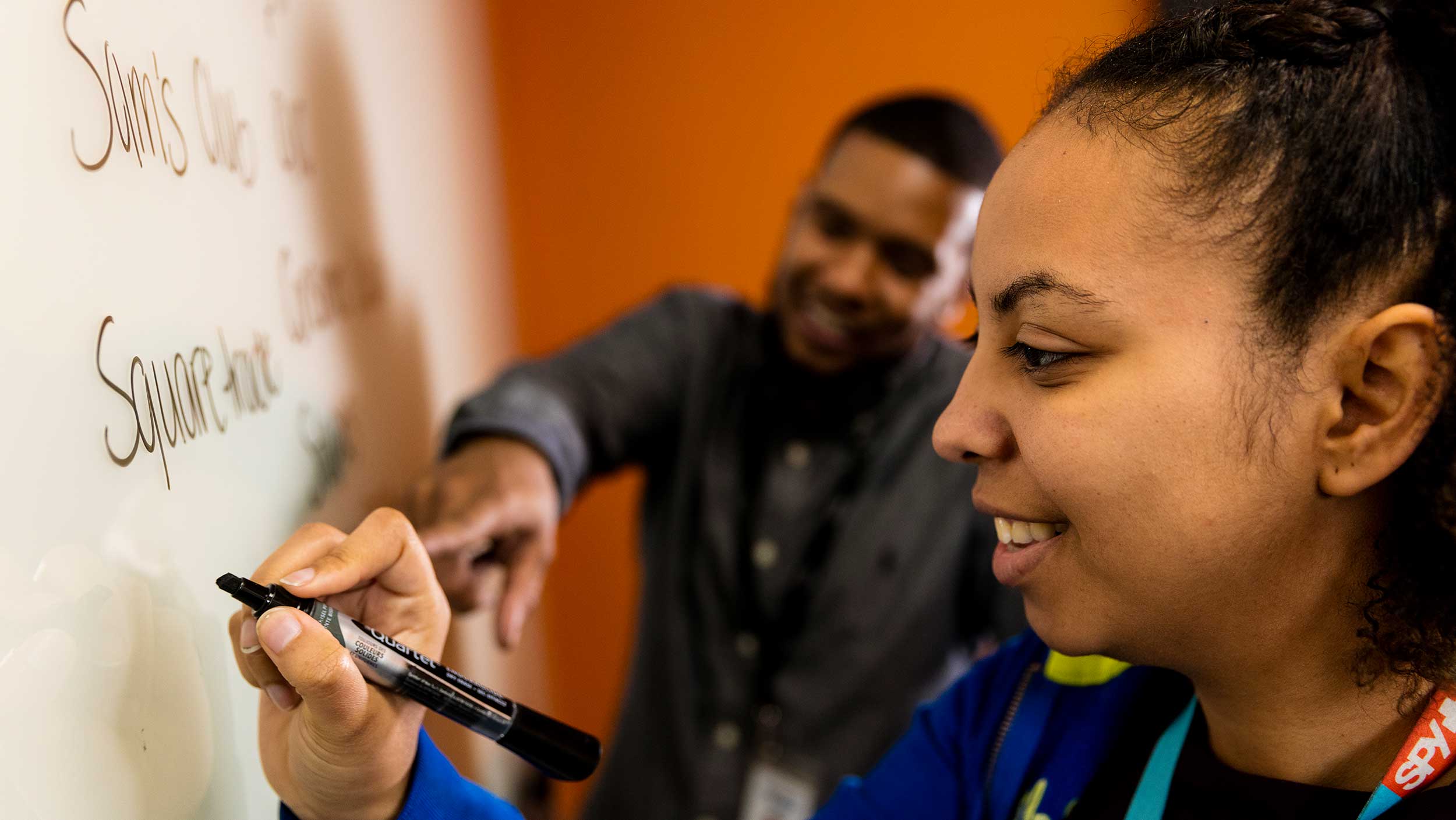 Two people writing on a whiteboard